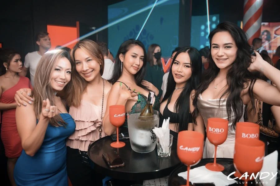 a group of women posing and smiling having fun in candy club