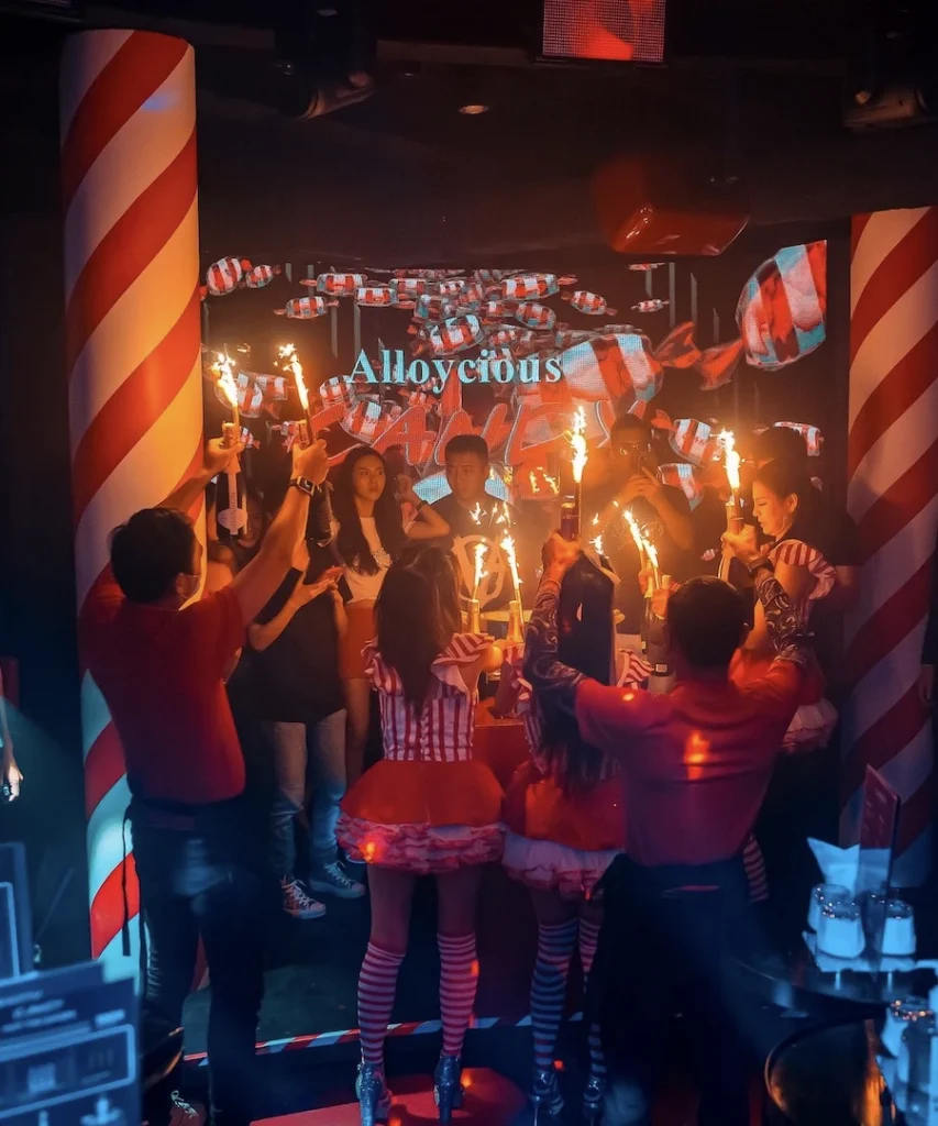 sexy girls bringing bottles of champagne equipped with sparklers in candy club