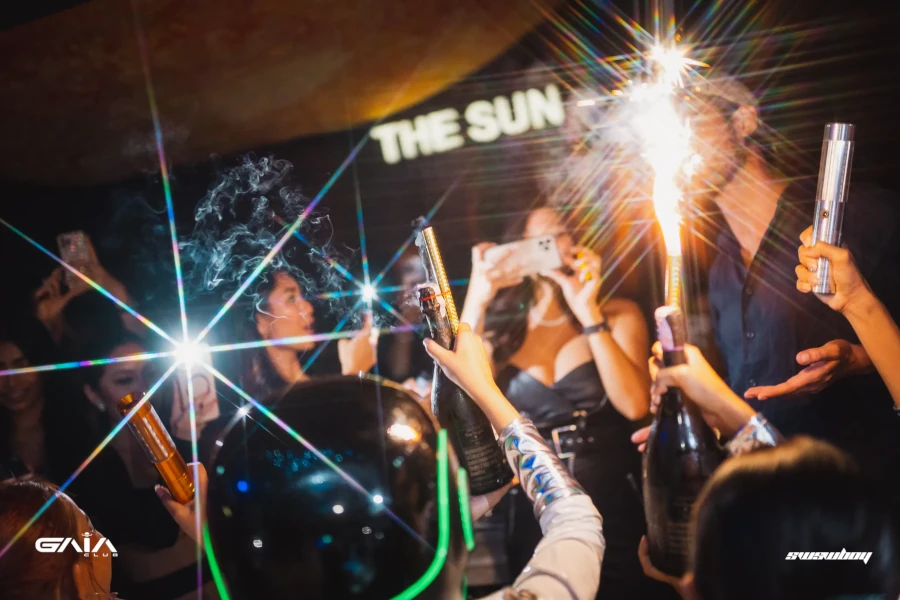 waitress serve some champagne bottles with sparklers at a party at gaia bangkok