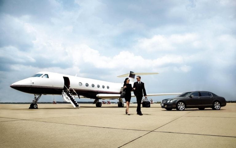 couple walking out of a private jet onto a luxury car