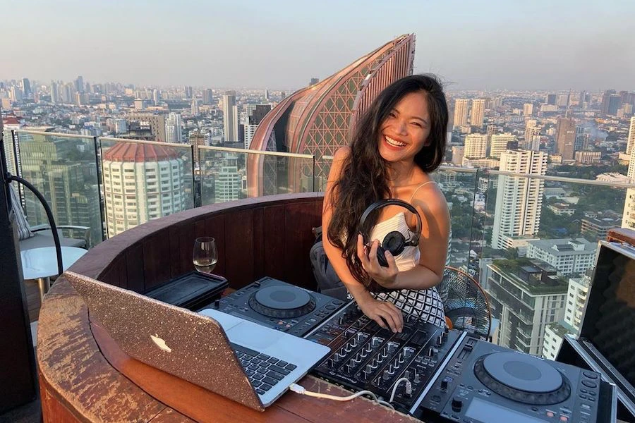 beautiful Thai female DJ smiling at the camera and holding her headphones at Octave rooftop bar in Thonglor Bangkok