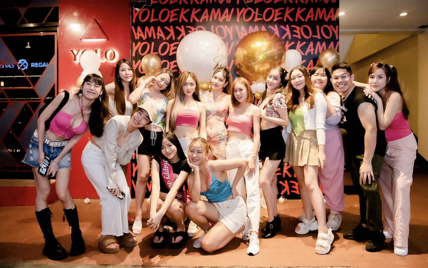 a large group of thai girls posing and smiling in front of yolo ekkamai bar