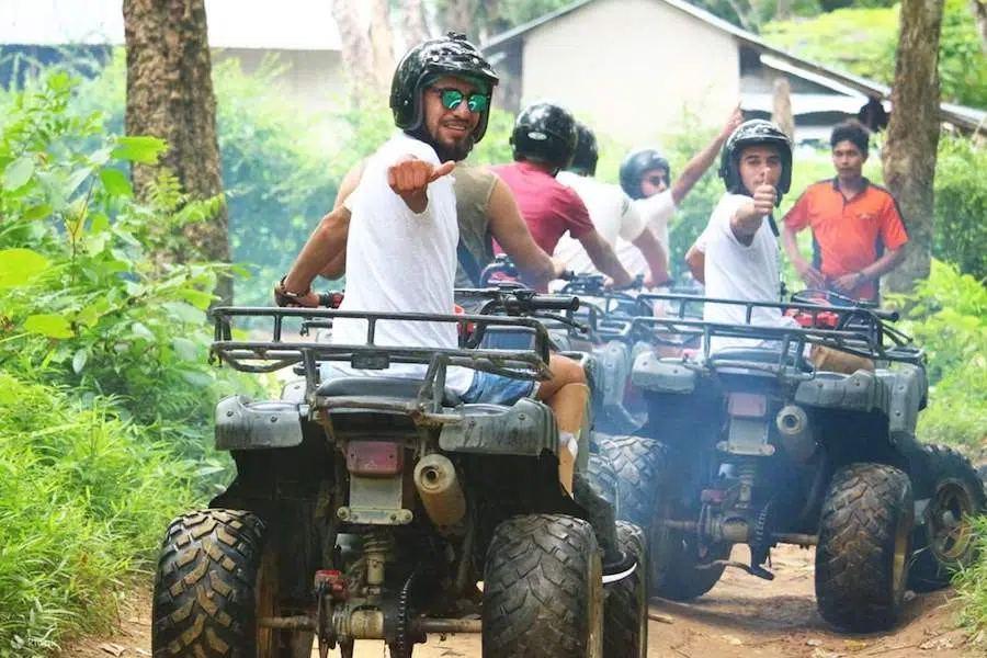 group riding ATVs in Bangkok giving a thumb up to the camera