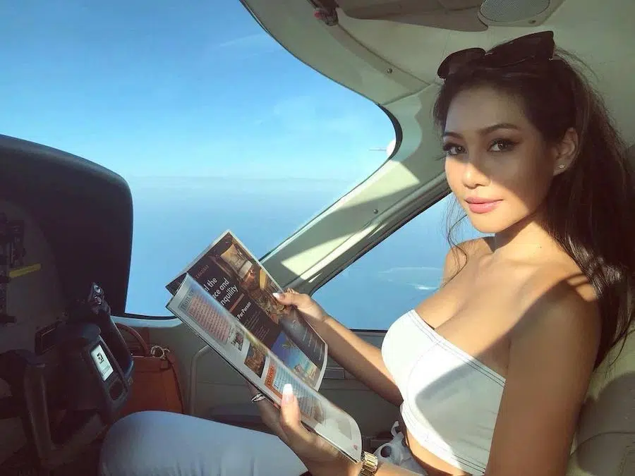 hot Thai girl reading a magazine in a private jet plane over the ocean
