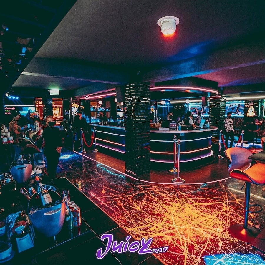 interior of Juicy Bangkok nightclub with central bar vip section and standing tables