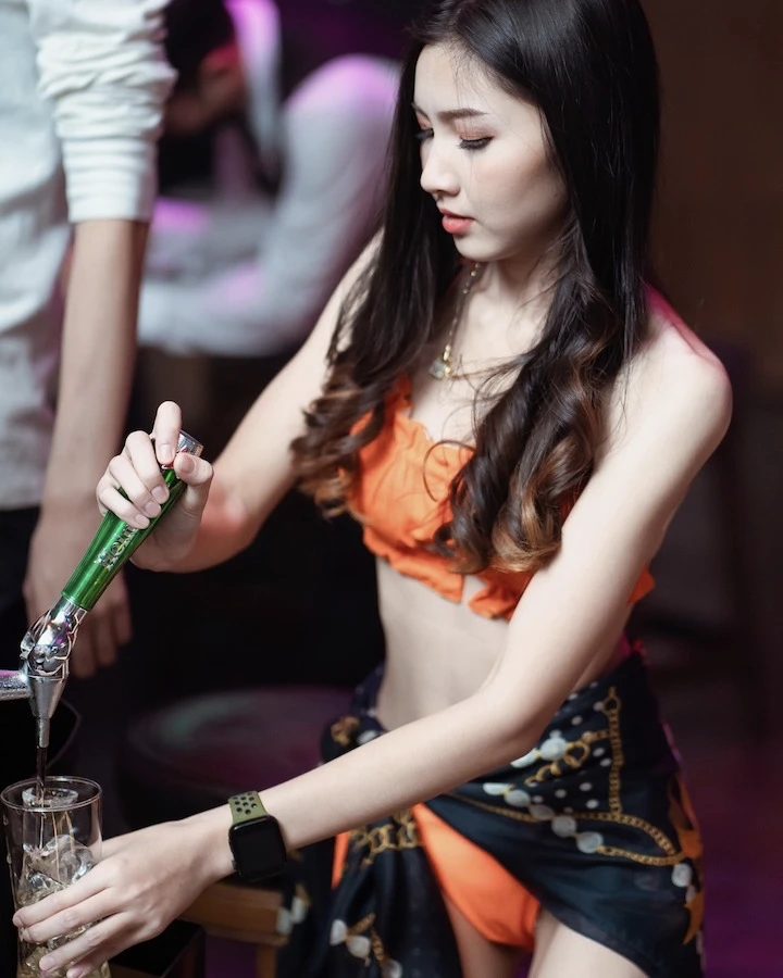 a girl in orange bikini serving beer in a club in bangkok