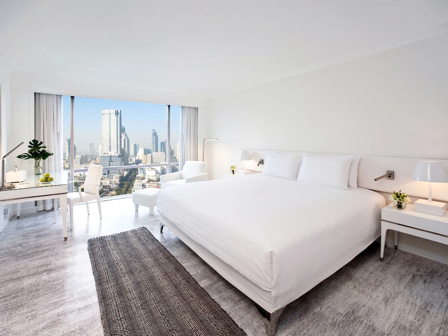 a large bed in a beautiful room at pullman bangkok hotel g with view of the city