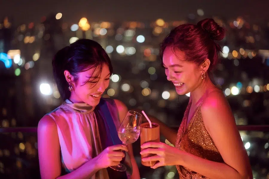 Thai girls drinking cocktails at a rooftop bar.