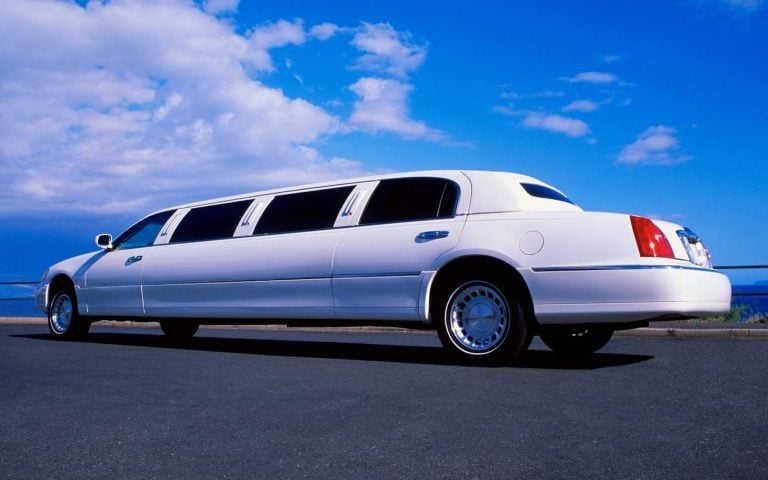 white stretch limousine on a road by the sea