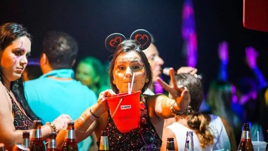 young girl drinking from a bucket at the full moon party in Thailand